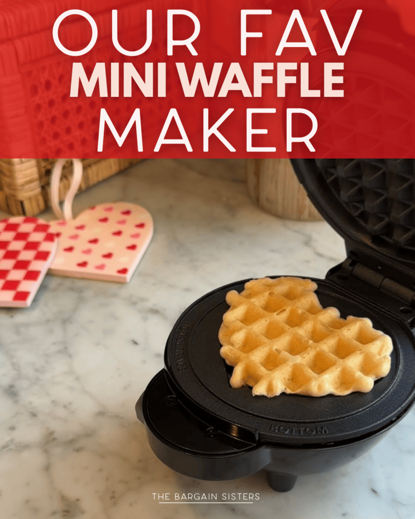 A mini waffle maker sits on a marble countertop, cooking a heart-shaped waffle. Heart-patterned trivets and woven baskets add charm in the background. The text reads, "Our fav mini waffle maker.