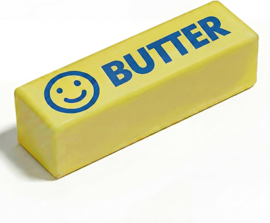 A rectangular stick of butter with the word "BUTTER" and a smiley face printed in blue on the wrapper, placed on a white background.