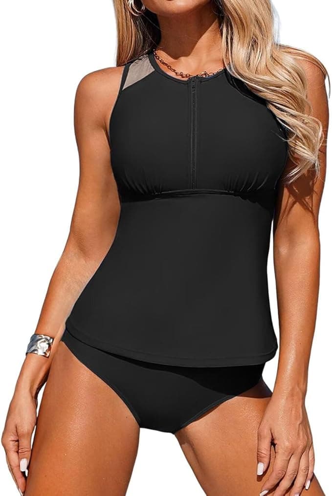 A woman wearing a black tankini swimsuit with a high neck and mesh detail at the shoulders, paired with matching black bikini bottoms. Shop this stylish women swimsuit now and enjoy 50% off. She accessorizes with a necklace and bracelet.
