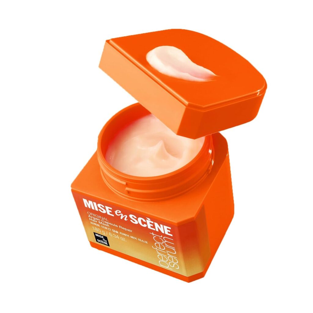 An open orange jar of Mise en Scène Damage Repair hair treatment cream, with a creamy, light pink product visible inside and some on the lid—perfect for nourishing your hair during Thursday Deals.
