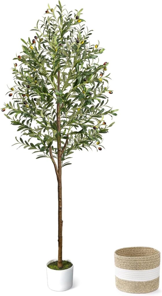 A tall artificial olive tree in a small white pot stands next to an empty woven basket with white stripes, against a plain white background.