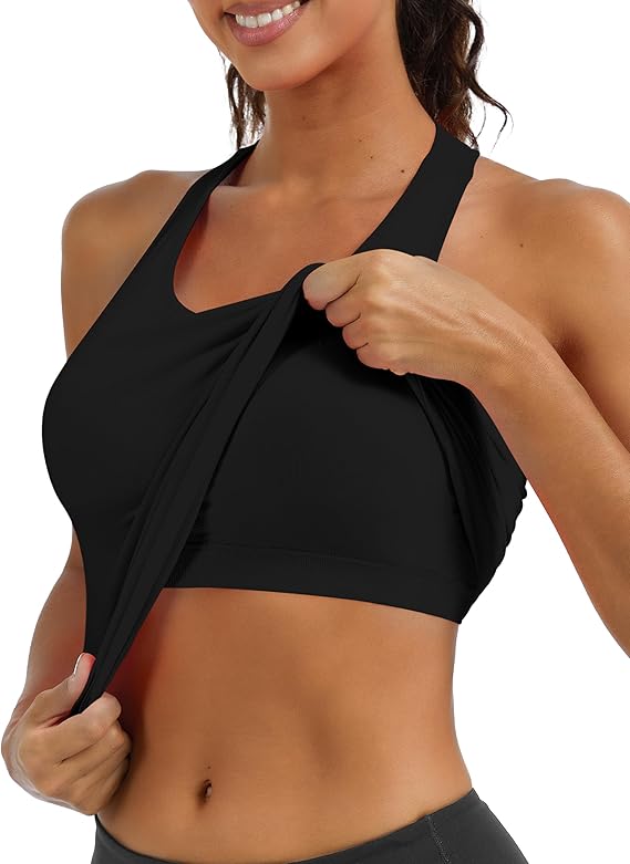 A woman wearing a black sports bra is lifting the outer layer of the bra to reveal a hidden inner layer, demonstrating its double-layered or nursing-friendly design.