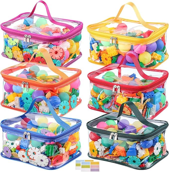 Six clear plastic zippered bags with colored handles, each filled with various colorful plastic building toys and shapes. The bags are arranged in two rows of three on a white background.