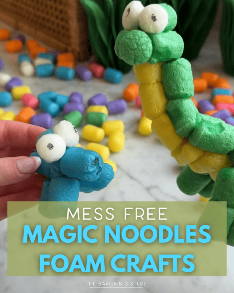 A hand holds a blue Magic Noodles creature with googly eyes next to a larger green and yellow foam dinosaur. Colorful foam noodles are scattered on a table in the background. Text overlay reads: "Mess Free Magic Noodles Foam Crafts for Kids.