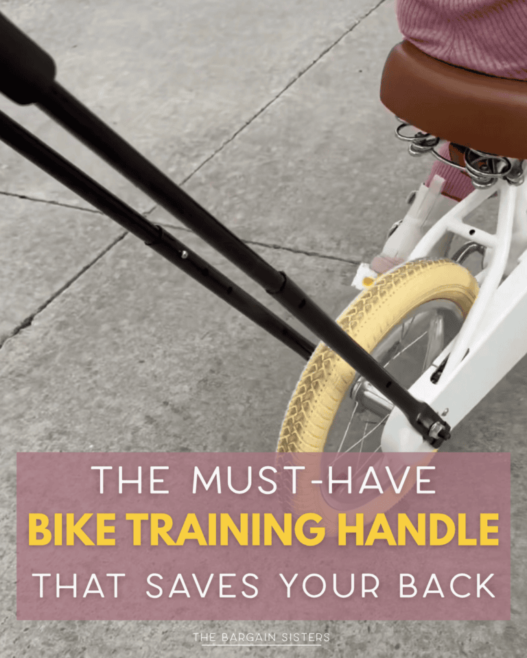 A child on a white bike with training wheels is guided by an adult using a long black bike training handle attached to the rear wheel. Text overlay reads: “The must-have bike training handle that saves your back.”.