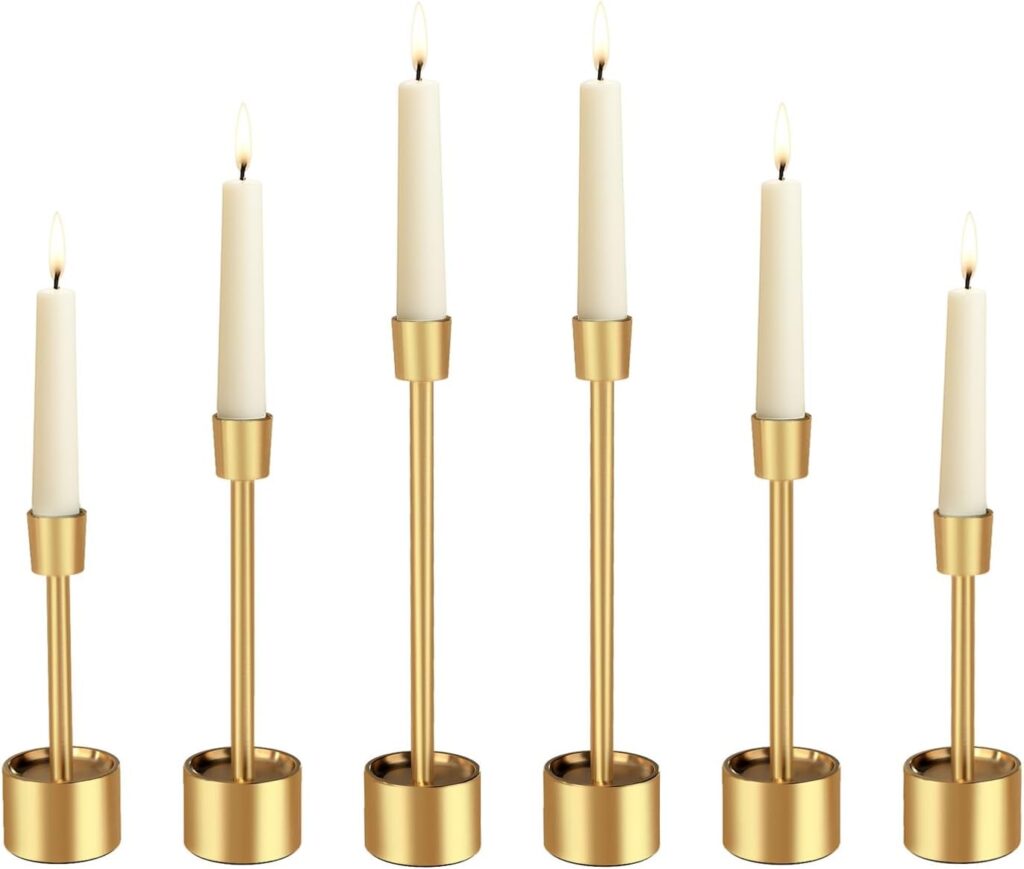 Six gold candlestick holders of varying heights, each holding a lit white taper candle, arranged in a row against a plain white background.