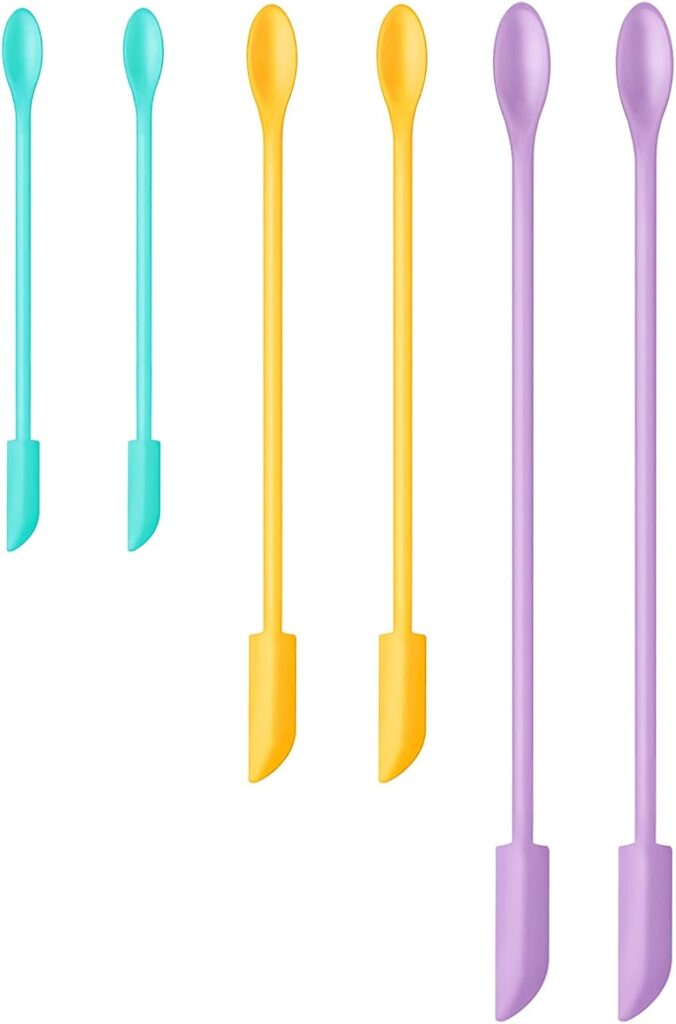 Six double-ended silicone spatula tools in teal, yellow, and purple, each with a small spatula on one end and a rounded tip on the other, arranged upright against a white background.