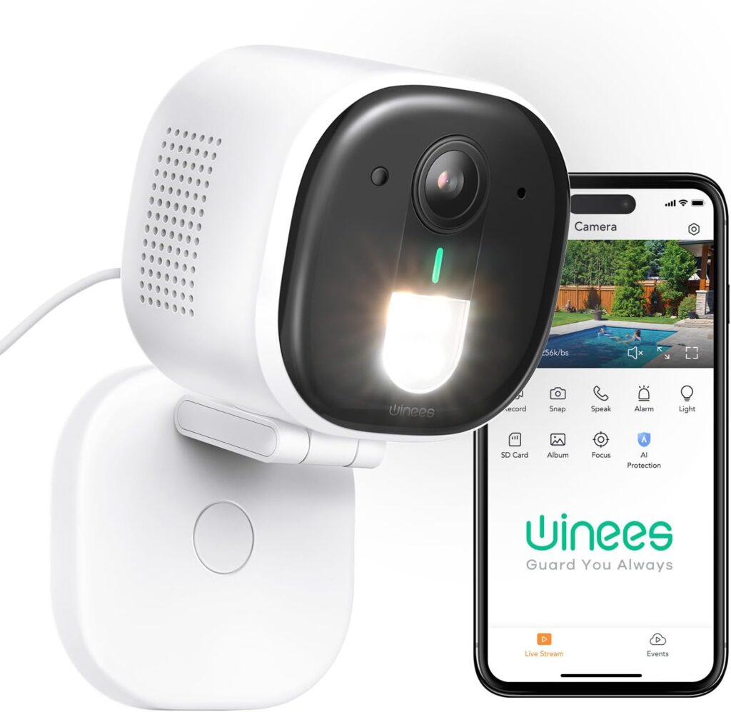 A white security camera with a glowing light is mounted on a wall. Next to it, a smartphone displays a live feed from the camera and the Vinees home security app interface.