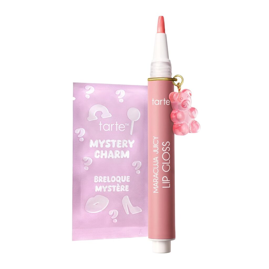 A pink tube of Tarte Maracuja Juicy Lip Gloss with a pink bear charm attached, shown next to a purple packet labeled "Tarte Mystery Charm" with white question marks and icons.