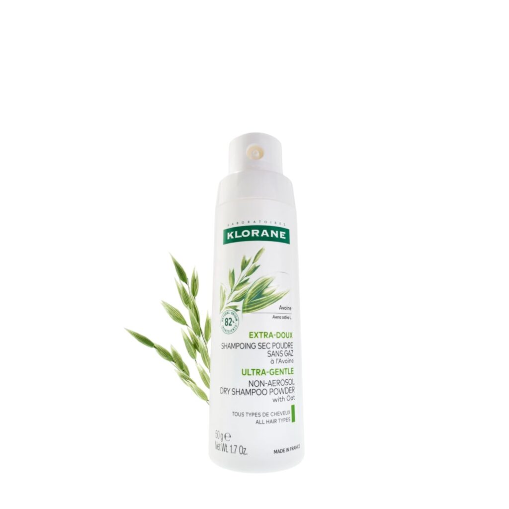 A white can of Klorane Ultra-Gentle Dry Shampoo Powder with Oat Milk, featuring green oat illustrations and product details, is shown alongside a small oat plant—perfect for snagging in this week’s Tuesday Deals.