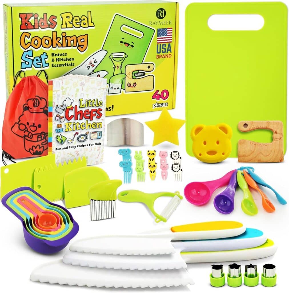 A colorful kids’ cooking set with knives, a cutting board, measuring spoons, vegetable peeler, crinkle cutter, bear-shaped tools, nesting measuring cups, recipe cards, and a red drawstring bag, all displayed in front of the box.