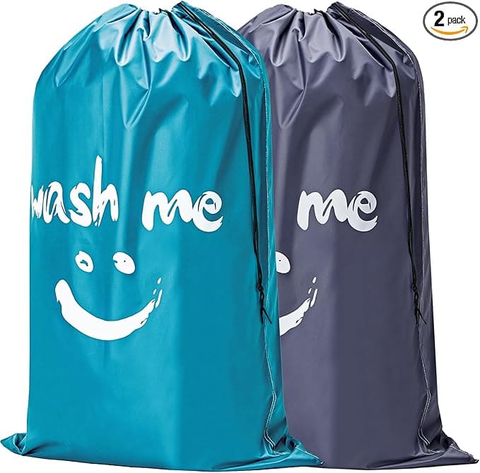 Two drawstring laundry bags, one teal and one dark gray, each with a white smiley face and the words "wash me" printed on the front. A "2 pack" label is shown in the upper right corner.