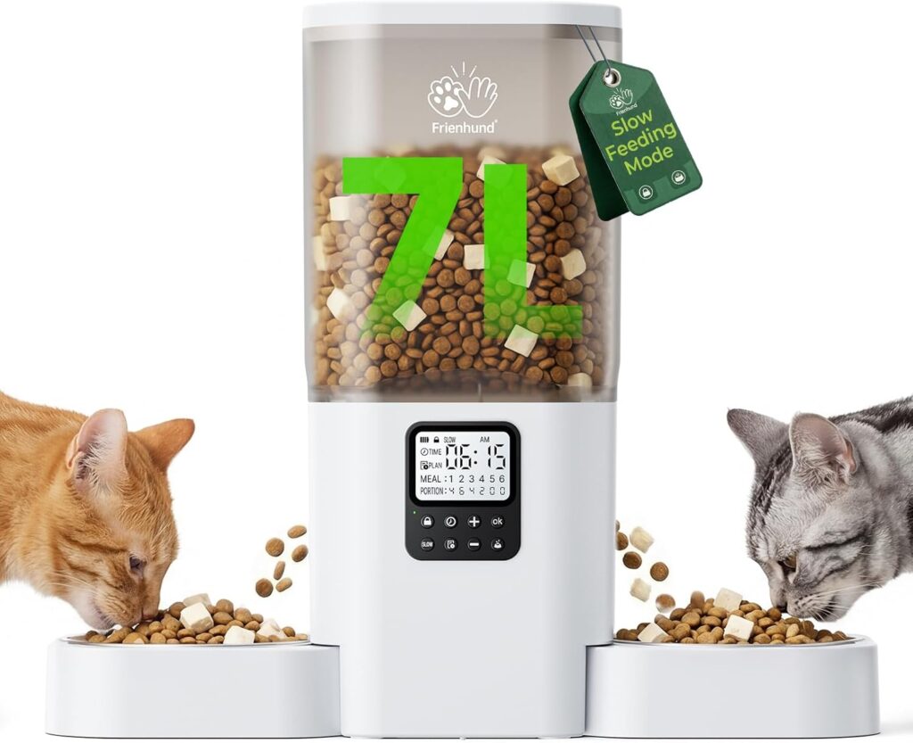 A white automatic cat feeder filled with dry food dispenses kibble into two bowls, each being enjoyed by an orange tabby cat on the left and a gray tabby on the right. The cat feeder displays "7L" and features a digital control panel.