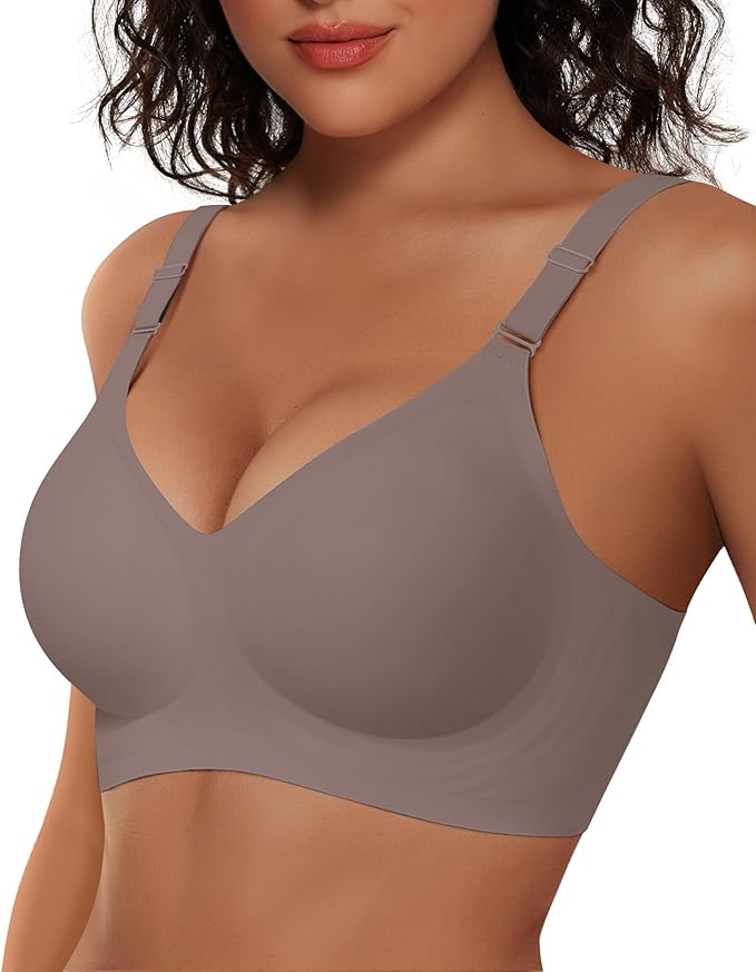 A woman with wavy dark hair models a seamless, wireless taupe bra with adjustable straps, showcasing the front fit and smooth fabric. Her face is partially visible from the nose down.