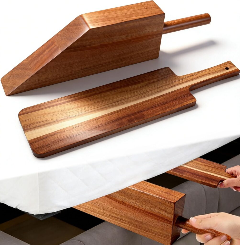 Two wooden cutting boards, one rectangular and one wedge-shaped, are shown on a white surface. A person slides the wedge-shaped board into a storage slot beneath a table—perfect for organizing your kitchen during Wednesday Deals.