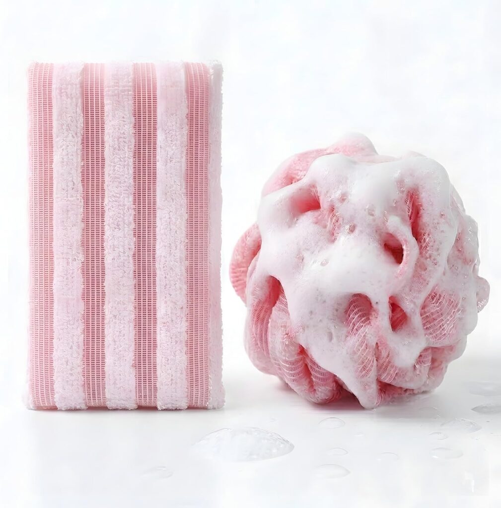 A pink striped bath sponge and a pink mesh loofah with white foam sit side by side on a white surface with water droplets—perfect for refreshing your routine with Tuesday Deals.