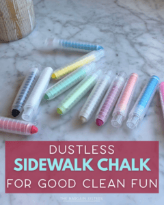 A set of colorful dustless sidewalk chalk sticks in clear plastic holders is arranged on a marble surface above a sign that reads, "Dustless Sidewalk Chalk for Good Clean Fun.