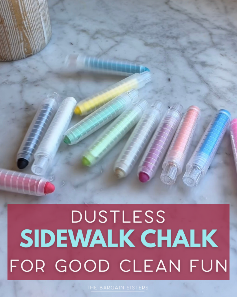A set of colorful dustless sidewalk chalk sticks in clear plastic holders is arranged on a marble surface above a sign that reads, "Dustless Sidewalk Chalk for Good Clean Fun.