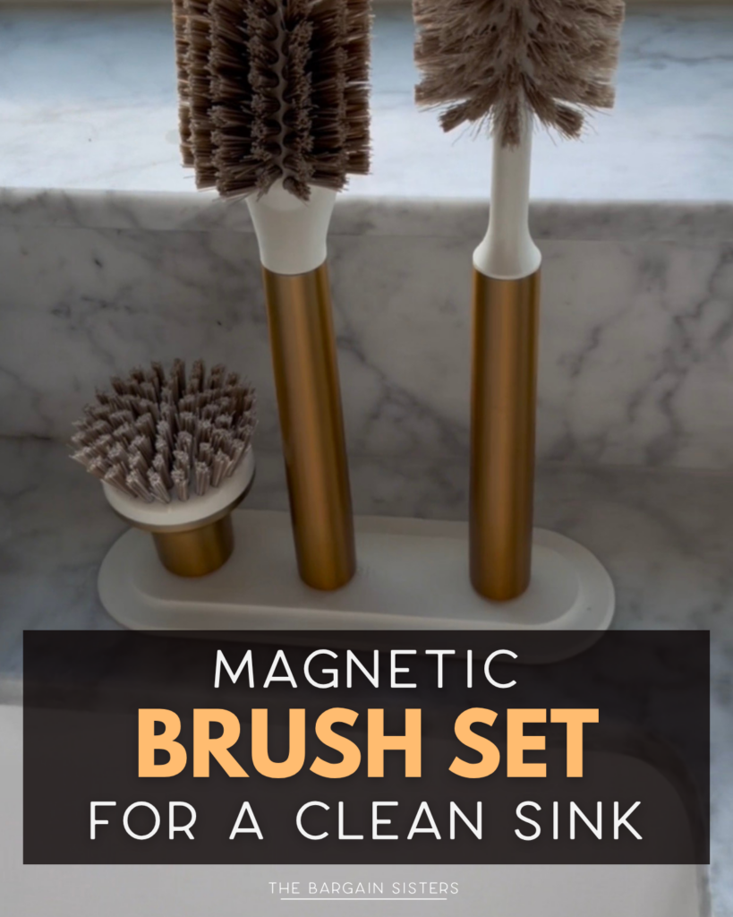 Three cleaning brushes with gold handles and brown bristles are attached magnetically to a matching stand on a marble countertop. Text overlay reads: "Magnetic Brush Set for a Clean Sink.