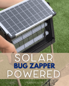 A person holds a solar-powered bug zapper with a solar panel on top, standing on grass. Text on the image reads "Solar Bug Zapper Powered - The Bargain Sisters.
