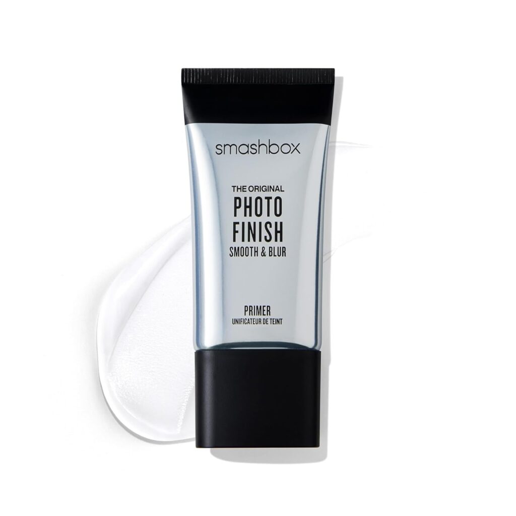 A clear tube of Smashbox Photo Finish Smooth & Blur Primer is shown on a white background with a smear of the clear primer behind it. The tube has a black cap and bold black text on the label.
