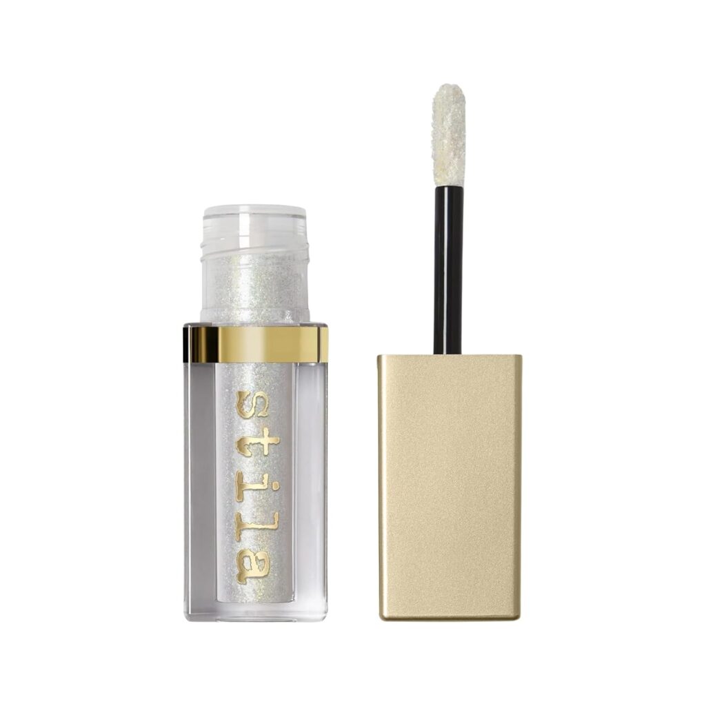 A clear tube of Stila liquid eyeshadow with a gold cap; the applicator wand, coated with shimmering white eyeshadow, is shown next to the open tube against a white background—perfect for scoring Monday Deals.