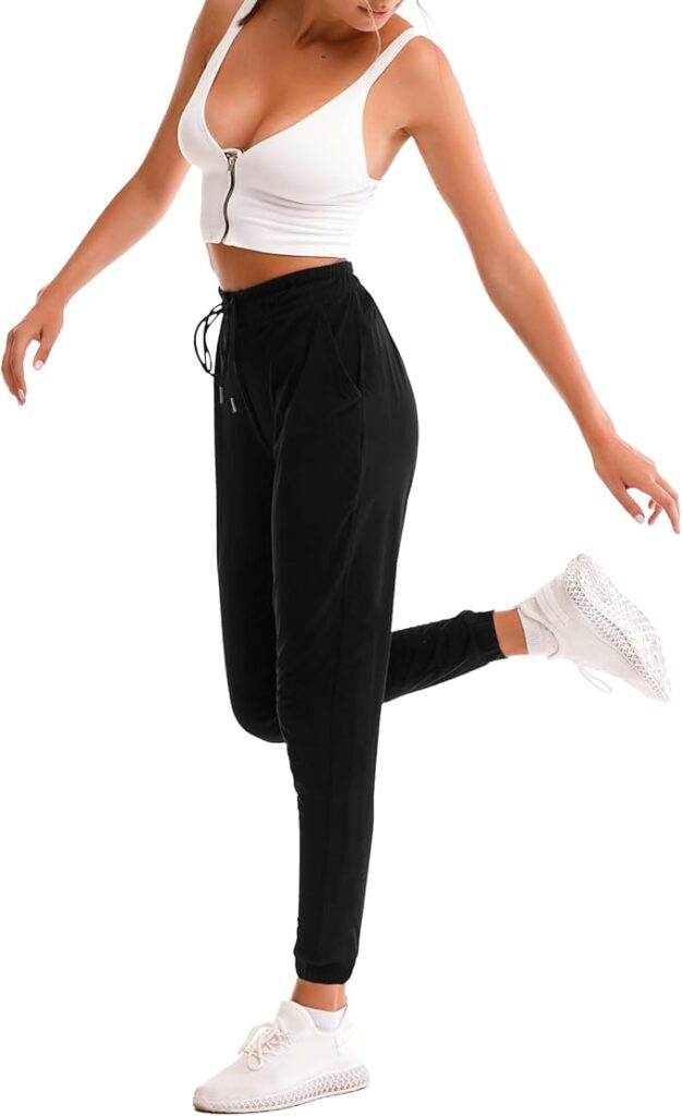 A person wearing a white crop top, black jogger pants, and white sneakers stands on one leg with the other leg bent backward, striking a pose against a white background—perfect for showcasing Thursday Deals.