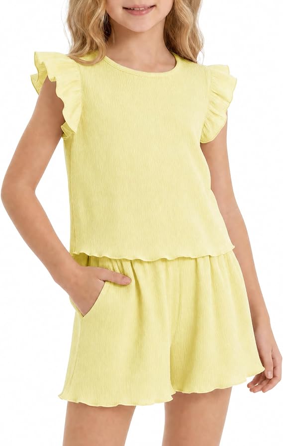 Young girl wearing a light yellow, short-sleeved ruffle top and matching shorts with scalloped hems, standing with one hand in her pocket—perfect for Tuesday Deals shopping.