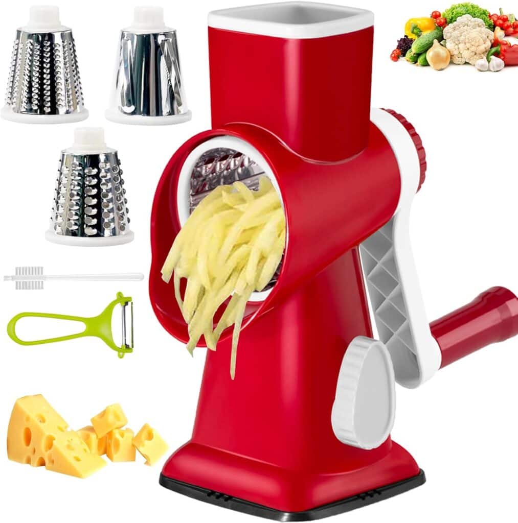 A red rotary cheese grater with shredded potatoes coming out, three interchangeable stainless steel drums, a peeler, a cleaning brush, cheese cubes, and assorted vegetables displayed nearby.