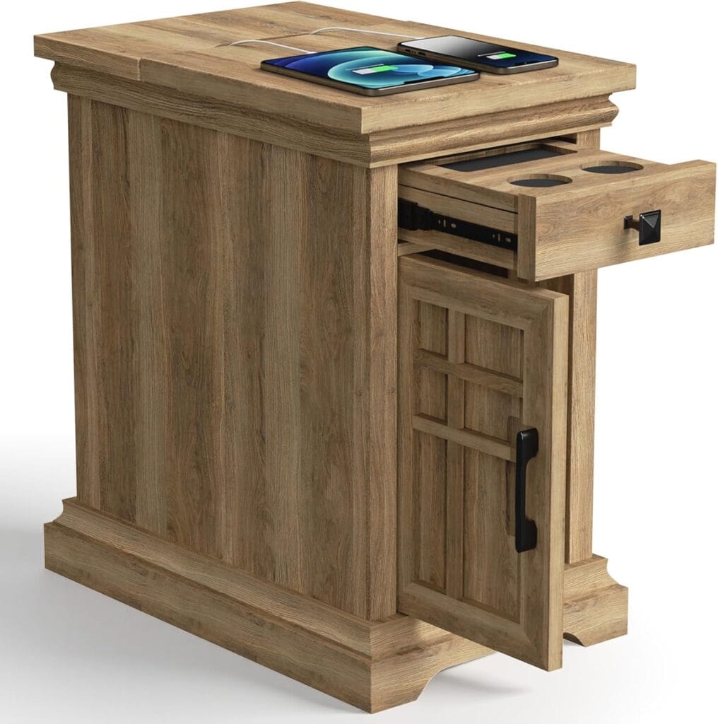 A wooden side table with a drawer and a cabinet door open, showing built-in cup holders and storage; the tabletop holds two smartphones and a tablet, all wirelessly charging.