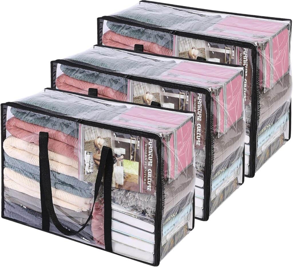 Three transparent storage bags with black handles, each filled with neatly folded clothes and bedding in various colors, are stacked next to each other. The bags have visible zippers and labels inside—perfect for organizing your space and taking advantage of exclusive Wednesday Deals.