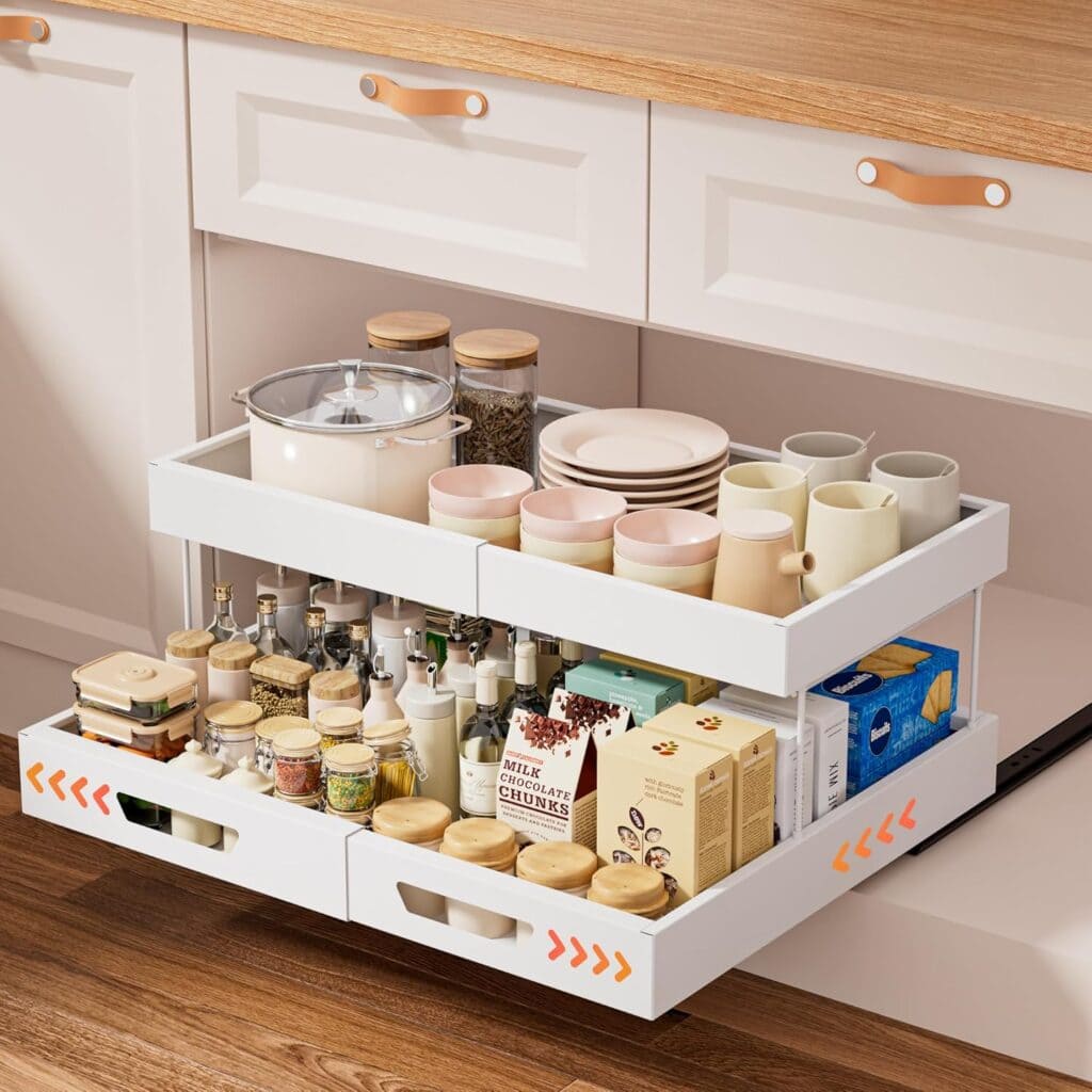A white pull-out kitchen drawer with organized shelves holds spices, jars, bottles, mugs, plates, and food packages. The countertop above is light wood, and the flooring is wood-patterned. The scene looks tidy and modern.