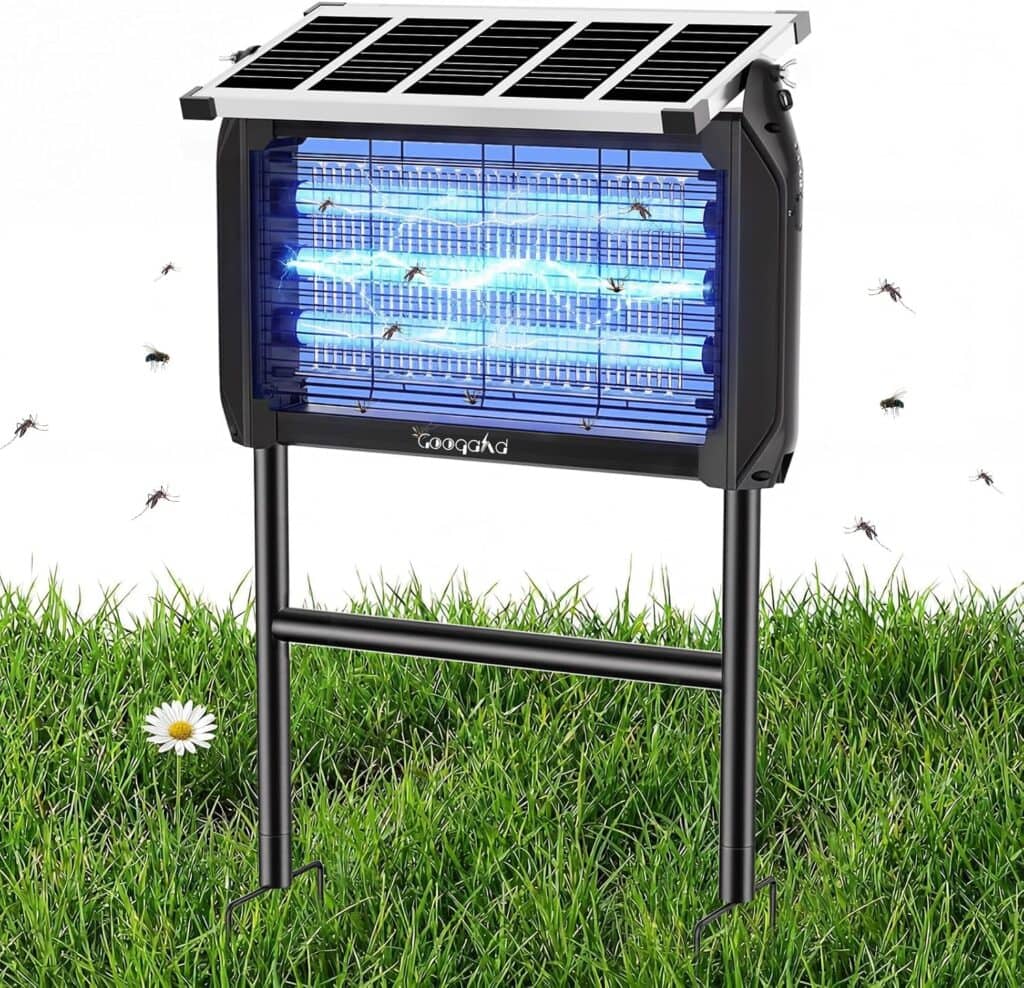 A solar-powered bug zapper with blue UV light stands on grass, surrounded by flying insects. The device is elevated on black legs and has a solar panel on top for charging. A white daisy is visible in the grass nearby.