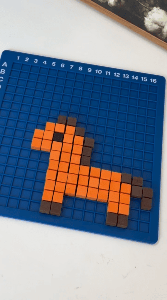 A blue grid board with small orange and brown blocks arranged to form the shape of a horse or pony.