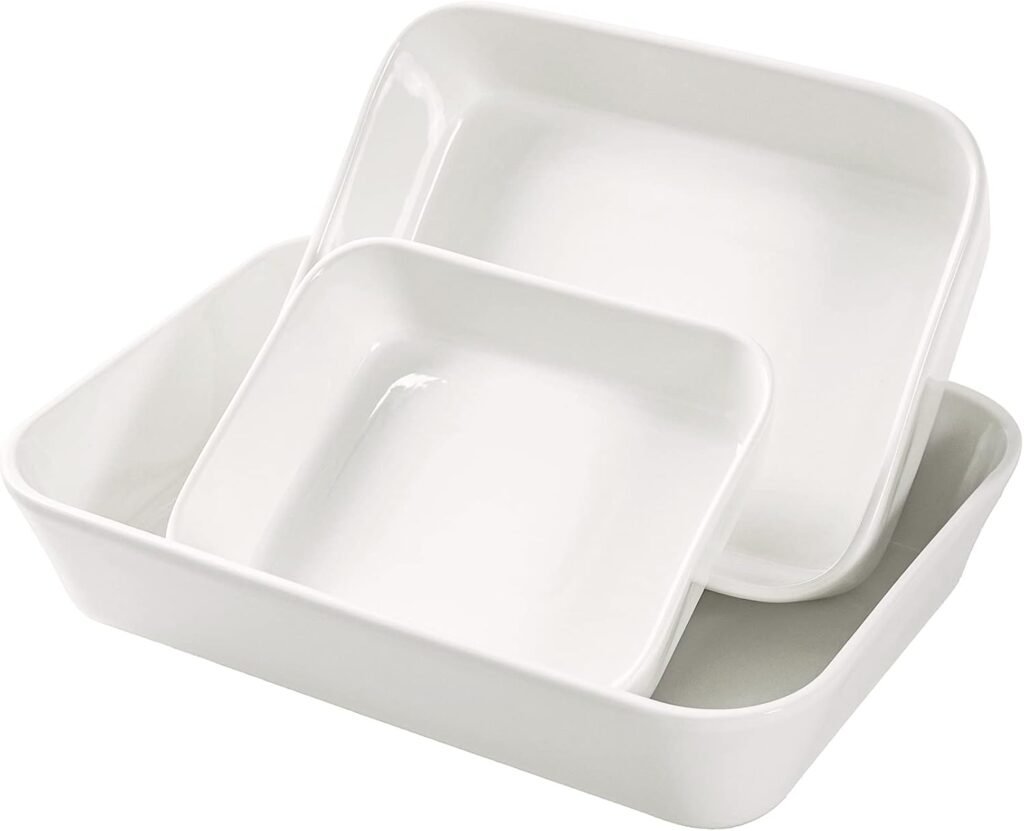 Three white rectangular ceramic baking dishes of different sizes are stacked together, with the smaller dishes nested inside the largest one.