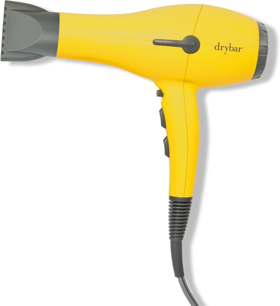 A yellow and gray Drybar hair dryer is shown on a white background, with its power cord hanging down and two control switches visible on the handle.