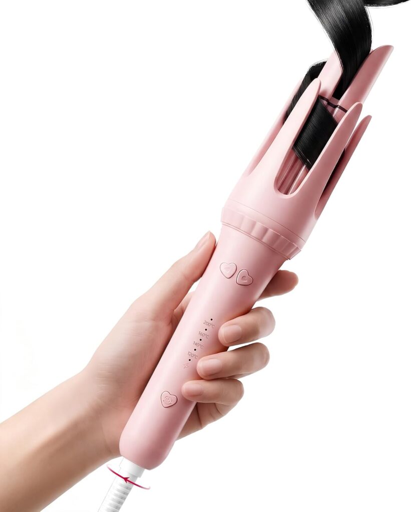 A hand holding a pink automatic hair curler with a strand of black hair wrapped around the curling barrel. The curler features heart-shaped buttons and a white power cord—perfect for styling during Friday Deals events.
