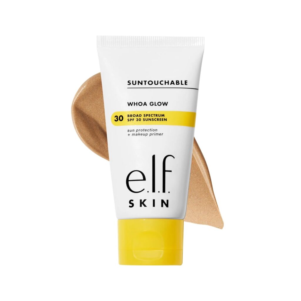 A tube of e.l.f. Skin Suntouchable Whoa Glow SPF 30 sunscreen is shown with a smear of the product's beige-colored cream in the background. The packaging is white with yellow accents.
