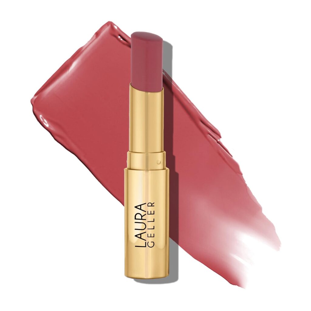 A gold tube of Laura Geller lipstick in a rose pink shade, shown against a swipe of the same color.