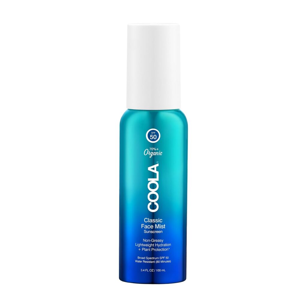 A blue bottle of COOLA Classic Face Mist Sunscreen SPF 50 with a white spray cap. The label mentions it is non-greasy, lightweight, and provides hydration and facial sun protection.