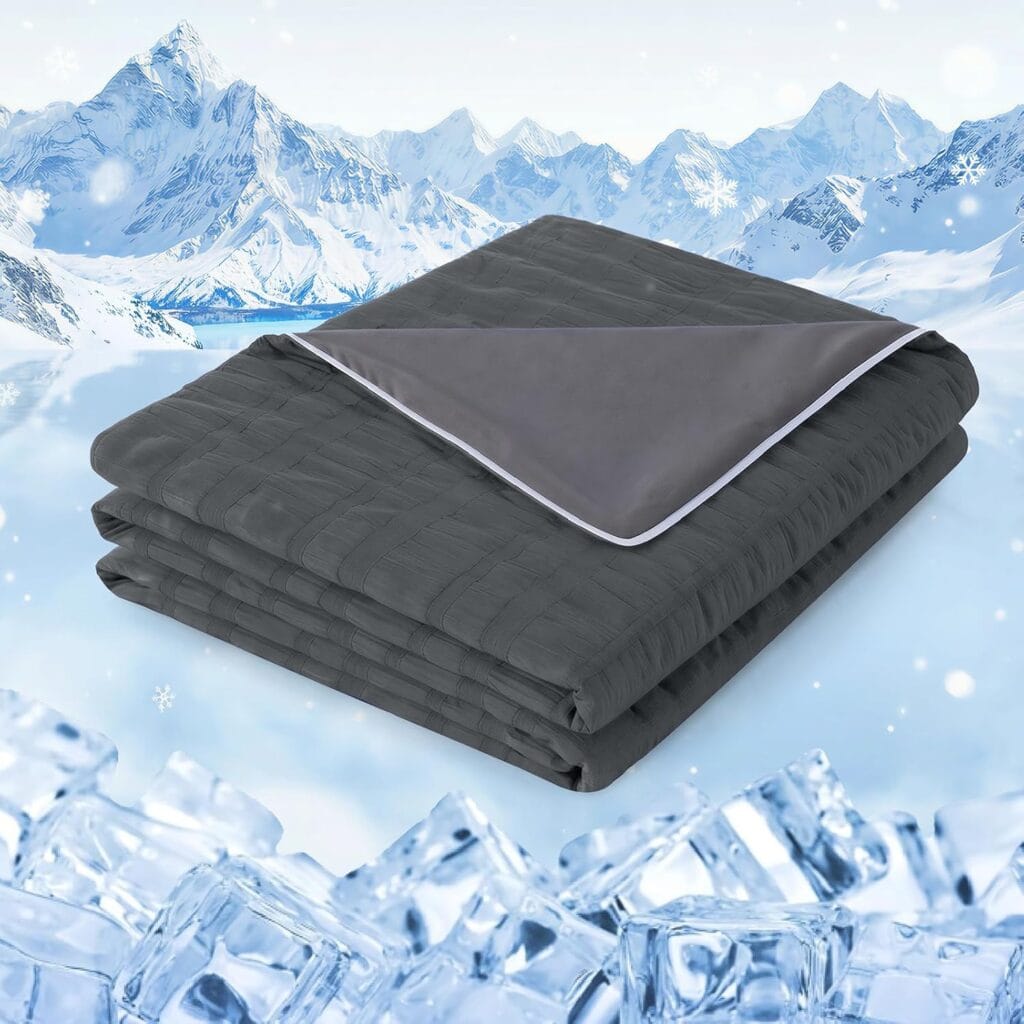 A folded gray blanket with a lighter gray inner lining is placed on ice cubes, with snowy mountains and a wintry sky in the background.