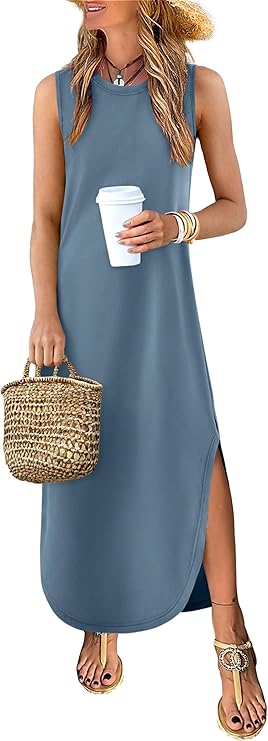 A woman in a sleeveless blue maxi dress with a side slit holds a woven straw bag and a white cup. She wears sandals, layered necklaces, bracelets, and a sunhat. Her hair is loose and wavy.