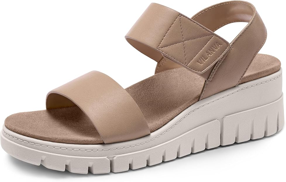 A stylish tan sandal with two wide straps, a thick cushioned sole, and a Velcro closure. The sole is white with deep grooves for traction. The brand name "VILANIA" is visible on the side strap.
