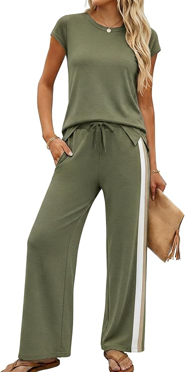 A woman wearing an olive green short-sleeve lounge set with white side stripes on wide-leg pants, holding a tan clutch and sporting sandals and a necklace—perfect for taking advantage of Wednesday Deals in effortless style.