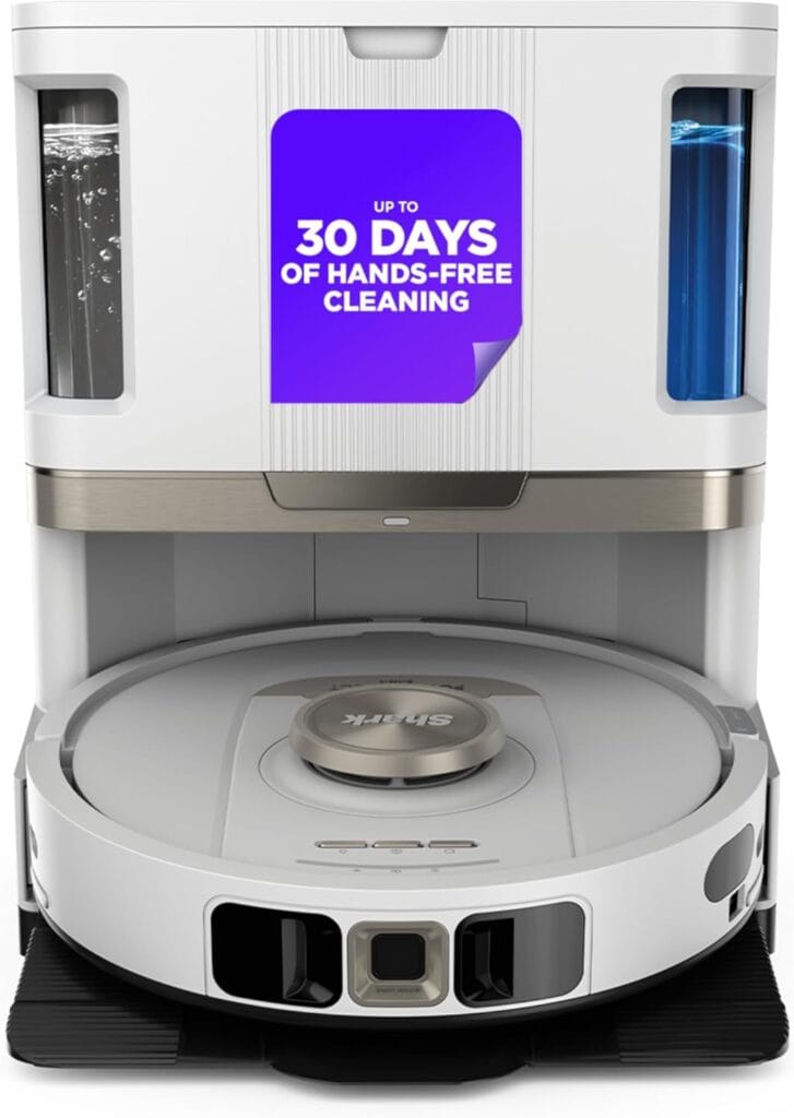A white Shark Stratos 2-in-1 robot vacuum sits in its charging station, with a sign stating "Up to 30 days of hands-free cleaning." Water tanks are visible on both sides of the station.