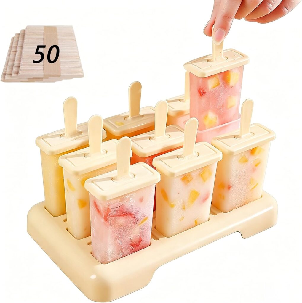 A hand lifts a homemade popsicle from a beige mold filled with fruit popsicles. A pack of 50 wooden sticks is shown in the upper left corner.