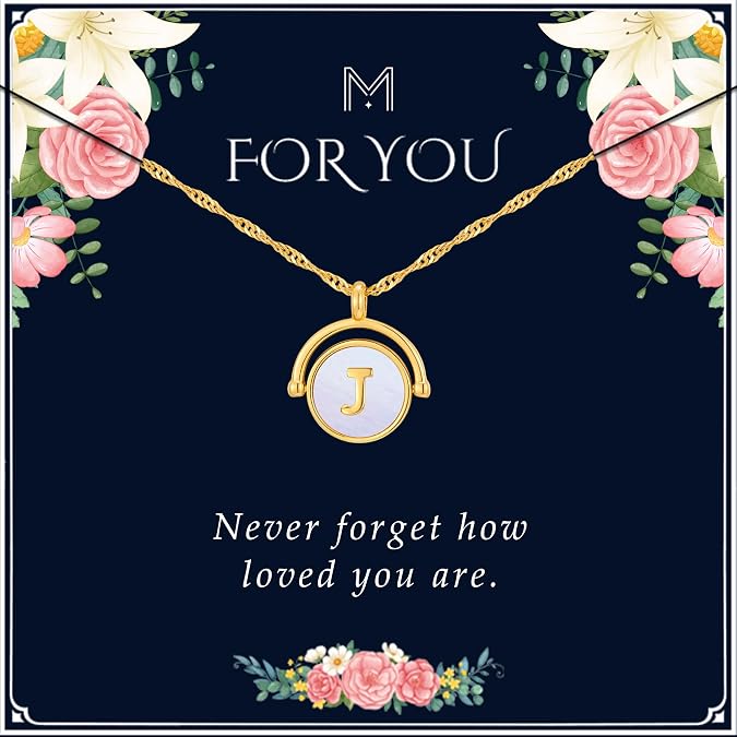 A gold necklace with a round pendant featuring the letter "J" on a white background, displayed on a dark blue floral card with the words "FOR YOU" and "Never forget how loved you are.