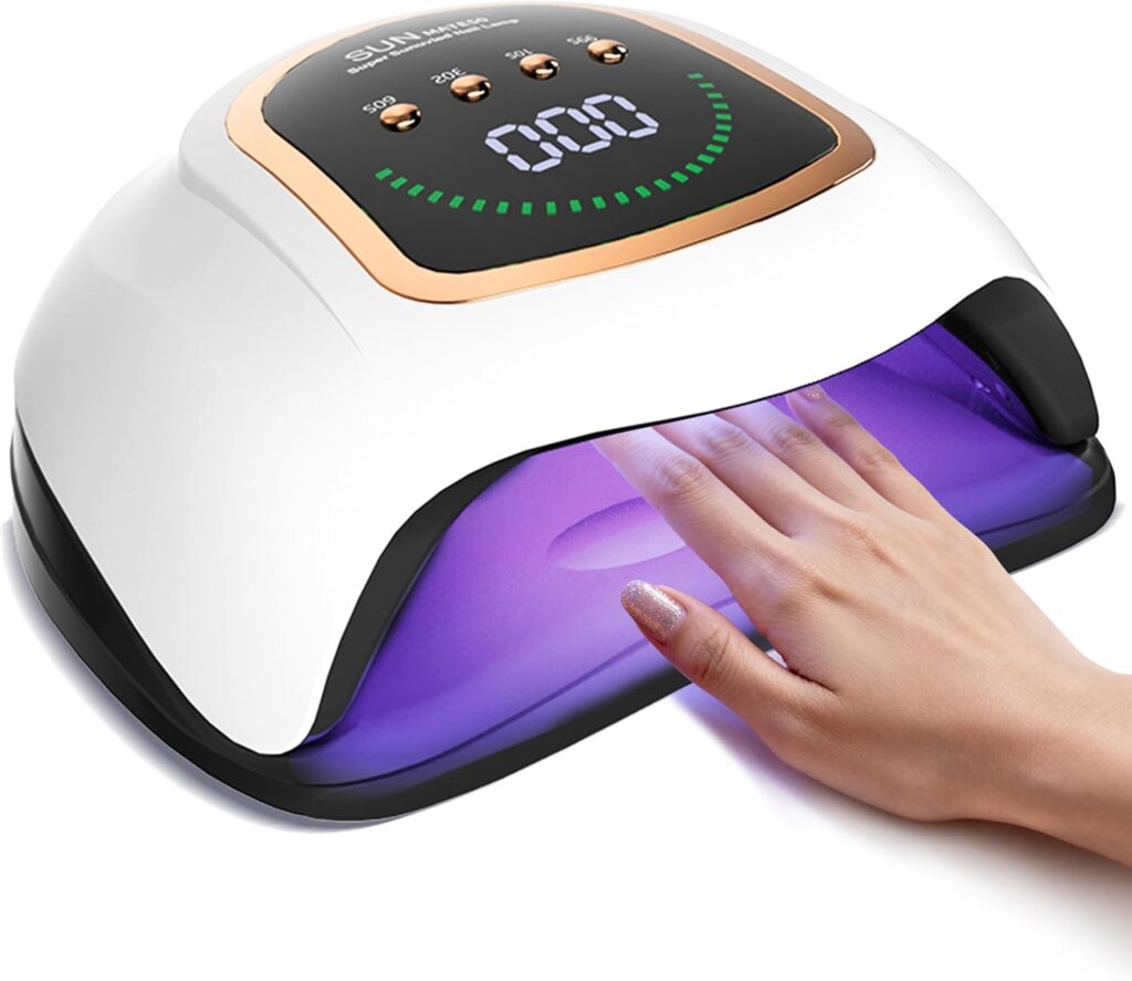 A hand is placed under a white and gold UV nail lamp with a digital timer display, curing gel nail polish with purple LED lights inside the device.