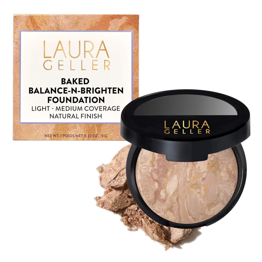 Laura Geller Baked Balance-n-Brighten Foundation in an open compact, showing marbled powder. The product box is behind it, displaying the brand name and product details. Some loose powder is scattered nearby.