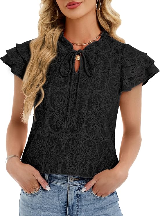 Woman wearing a short-sleeve black lace blouse with ruffled sleeves, keyhole neckline with tie, and light blue jeans. She has long wavy blonde hair and accessorizes with hoop earrings, bracelets, and layered necklaces.